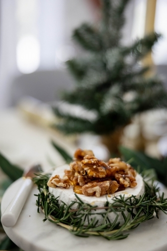 Dish of Camembert with rosemary and walnuts on decorated Christmas table