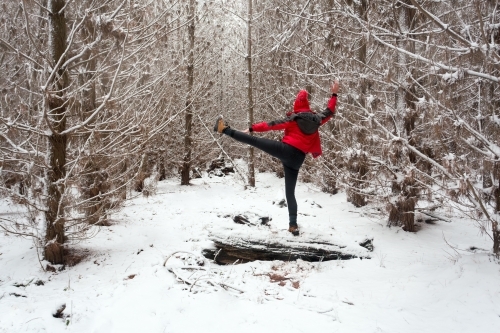 Exercising and stretching in the snow while balanced on log