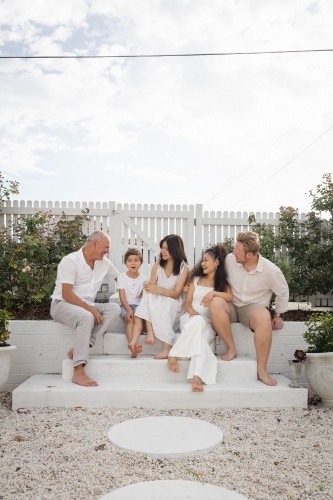 Family of five sitting on backyard steps