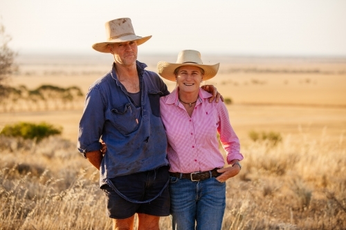 Farming couple wearing hats on their rural property
