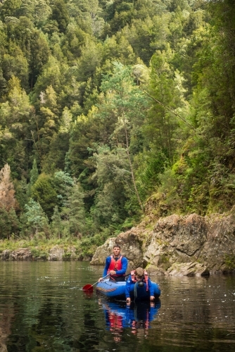 Father and son kayaking down tranquil lush river