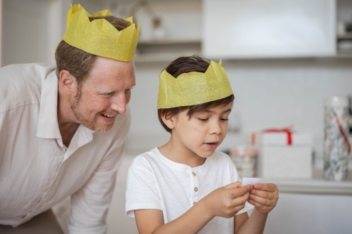Father and son wearing yellow crowns reading Christmas cracker joke