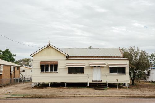 Front-on view of cream coloured Queenslander Home with brown trimming