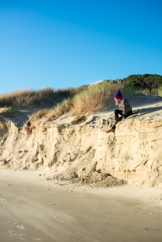 Girl climbing on sand dunes at beach late on a winter day nearly at sunset