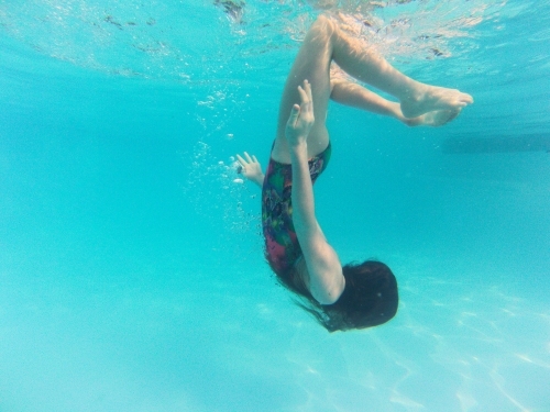 Girl doing somersaults underwater in a pool
