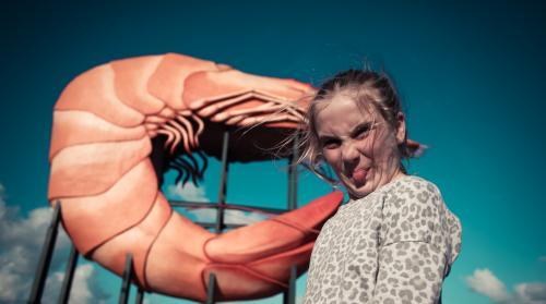 Girl making a face in front of a big prawn