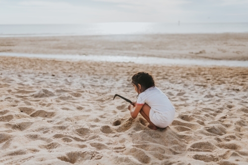 Girl playing in sand at the beach
