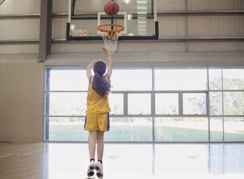 girl shooting basketball hoop.