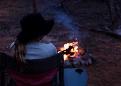 Girl sitting by campfire in the bush