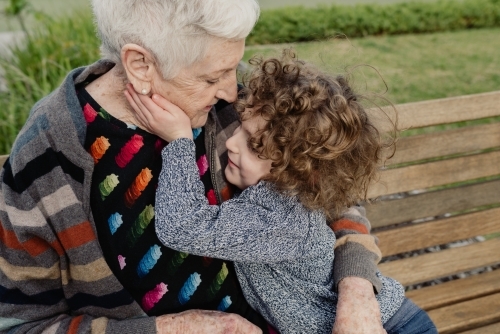 Grandmother and grandson hugging on a park bench