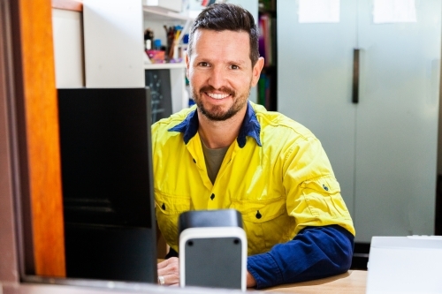 Happy male tradie at computer in home office