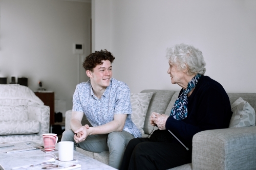 Horizontal shot of a teenage boy and and old woman talking