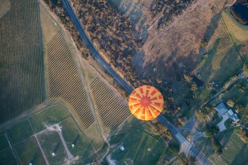 Hot air balloon appears to be travelling on road.