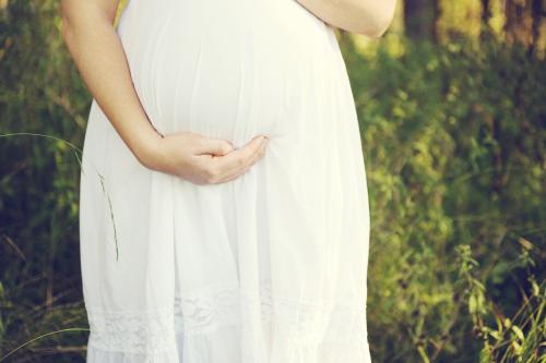 lady in white dress holding her pregnant belly