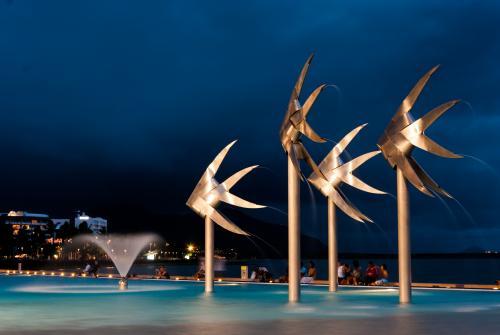 Lit up Sunfish statues and fountain in public pool on foreshore with people in background