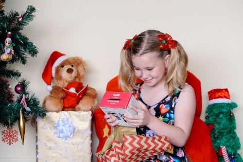 Little blonde girl happily looking at a present she has unwrapped on Christmas day