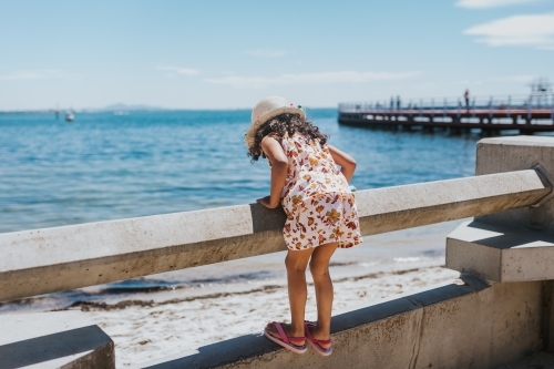 Little girl looking at the sea over railing