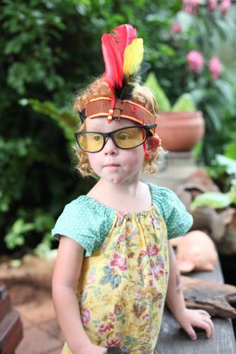 Little girl wearing dress up Indian headband and glasses