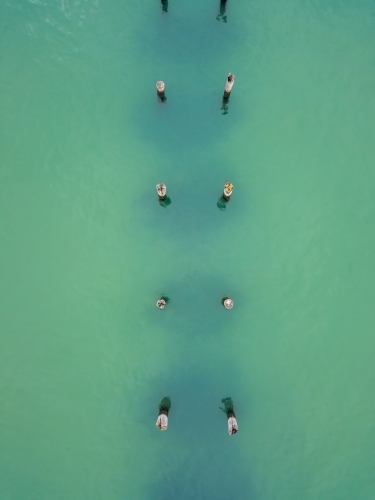 Looking down on a row of old jetty pylons in turquoise water