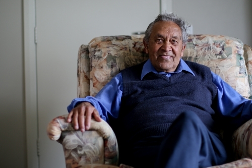 Male Aboriginal elder sitting in an armchair in his home