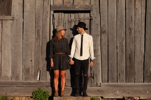 Man and woman holding hands standing against rustic wooden wall