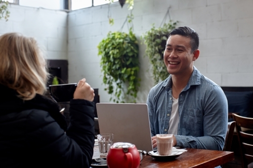 Man enjoying time with friend over coffee at cafe