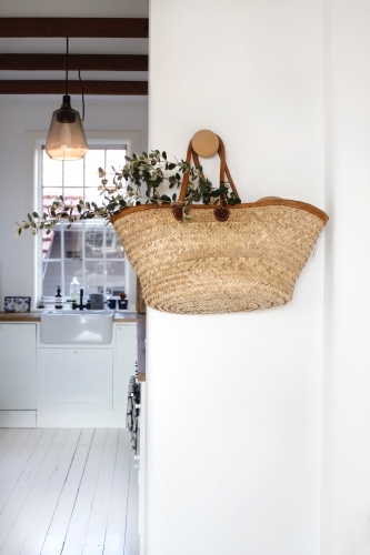 Market basket with eucalyptus leaves hanging on white wall with kitchen background