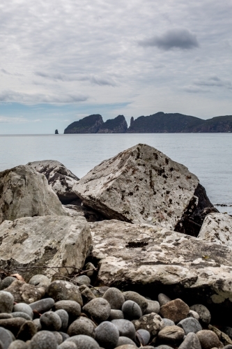 Massive boulders covered in white lichen line the coast  as Cape Hauy rises in the background