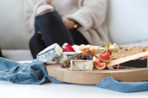 Close up of cheese platter with blurred seated woman in background