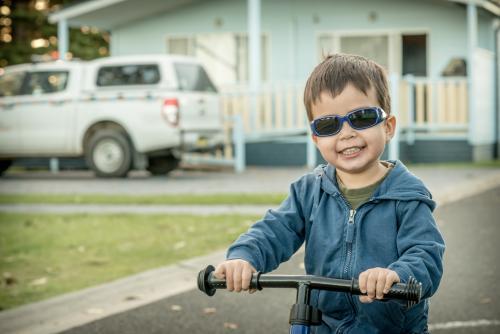 Mixed race boy wearing sunglasses and riding his bike in a coastal NSW holiday park