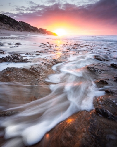 moving water over coastal rocks at sunrise