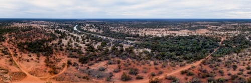 Panorama of red outback land with low green scrub