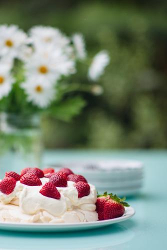 Pavlova topped with strawberries set out on a table outdoors in summer