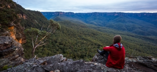 Person sitting on a rock looking out over a valley in the Blue Mountains