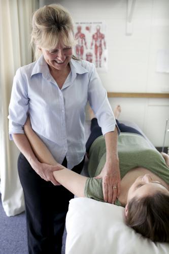 Physiotherapist treating patient with shoulder injury