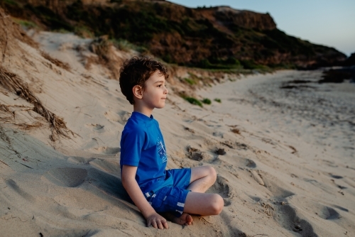 Portrait of a happy young boy relaxing on on the beach at sunset