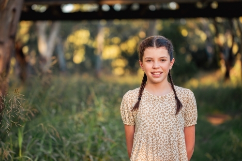 Portrait of happy pre-teen girl wearing dress in Australian country bush setting