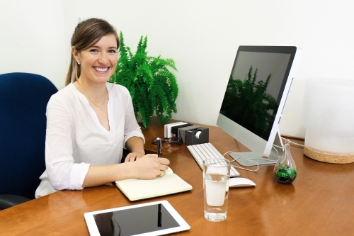 Portrait of young professional woman looking at camera from her office desk