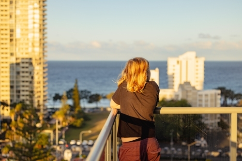 Pre-teen boy standing on balcony of high rise building on the Gold Coast with view of city
