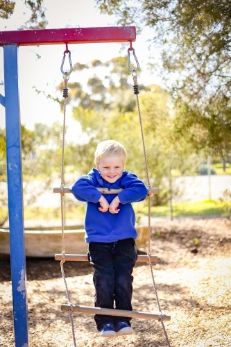Preschool age child posing on rope ladder swing for kindergarten photos. Portrait of young boy.