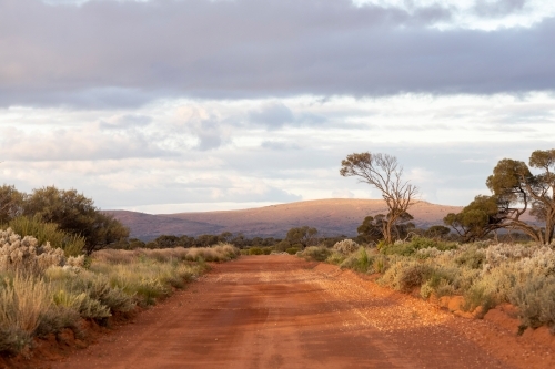red dirt road with hills in background