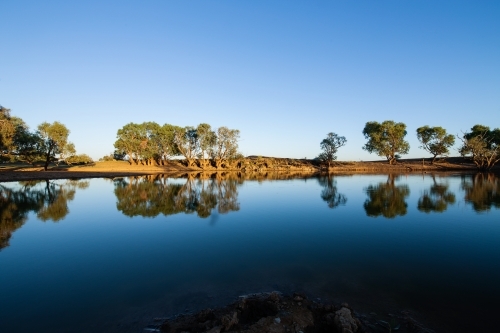 reflections on a dam under a blue sky