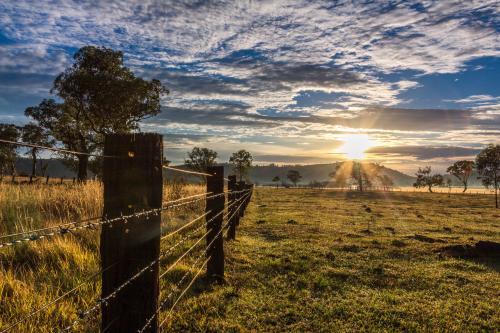 Rural farm fence leading to sunrise
