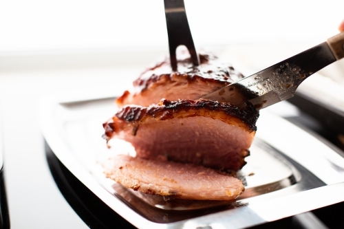 small baked glazed ham being sliced to serve