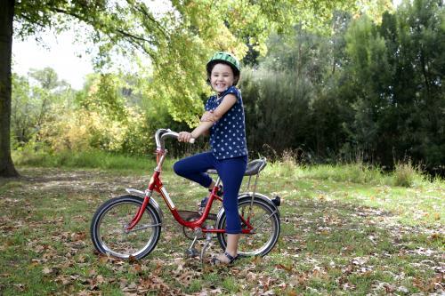 Smiling girl wearing helmet with red bike