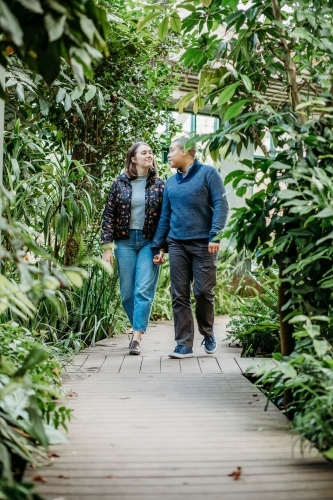 smiling lgbtqi couple holding hands while looking at each other walking in a garden
