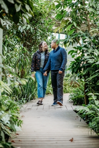 smiling lgbtqi couple holding hands while looking at each other walking in a garden