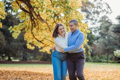 smiling lgbtqi couple hugging each other by the autumn trees