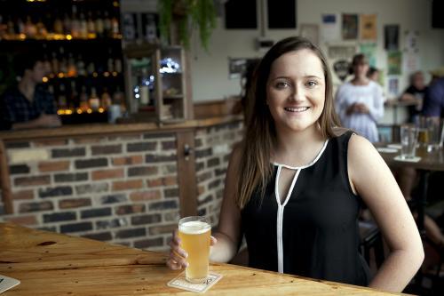 Smiling woman enjoying a drink at a local craft beer bar