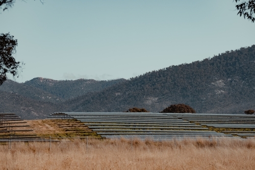 Solar farm panels on a hill for renewable energy with mountains in the background.